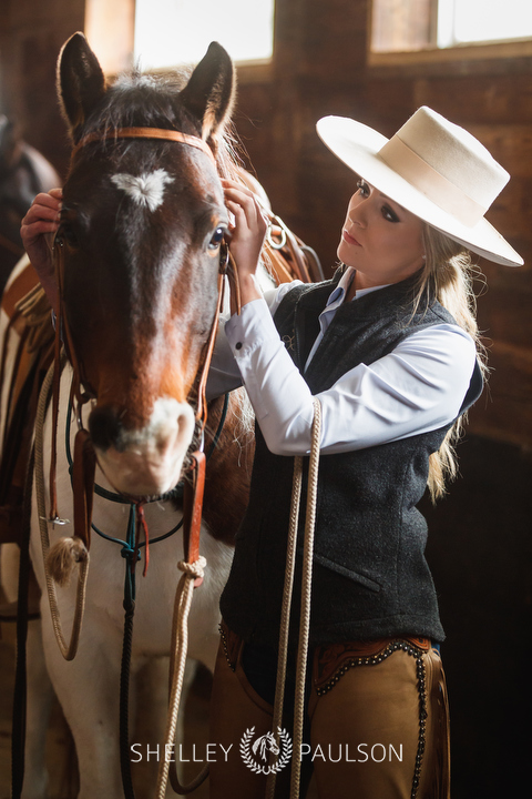 Photo of a woman bridling a horse