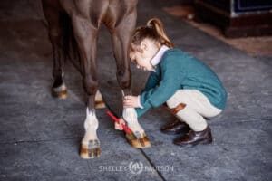 Photo of a girl polishing her pony's hooves