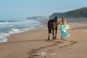 Girl walking with her horse on the beach